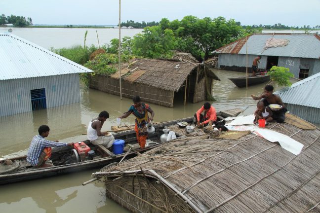 バングラデシュで屋根の上に避難する人や小舟の上で煮炊きをする人々
