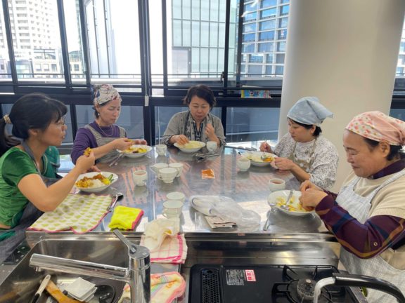 ベンガルカレーを手で味わう職員と運営スタッフ